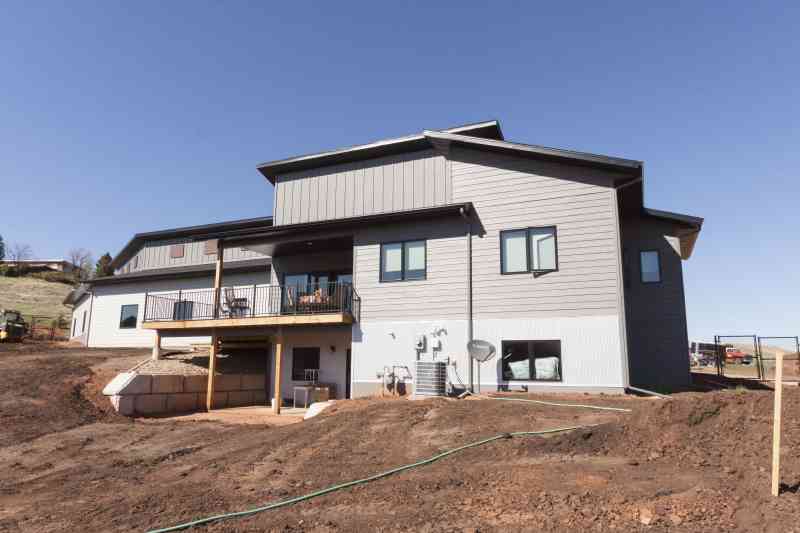 The back of the home including the large deck and the second story's decorative rusted plates.