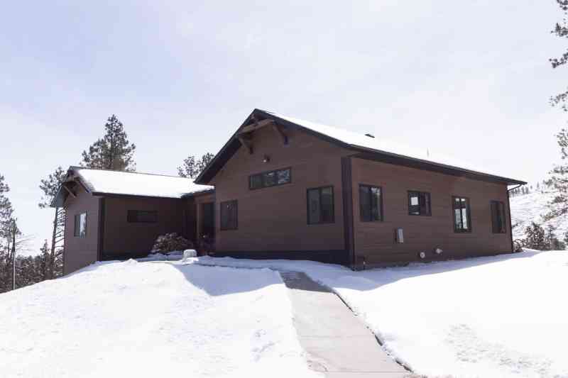 This modern, rustic home is sided with wood-tone engineered siding and black metal corners.
